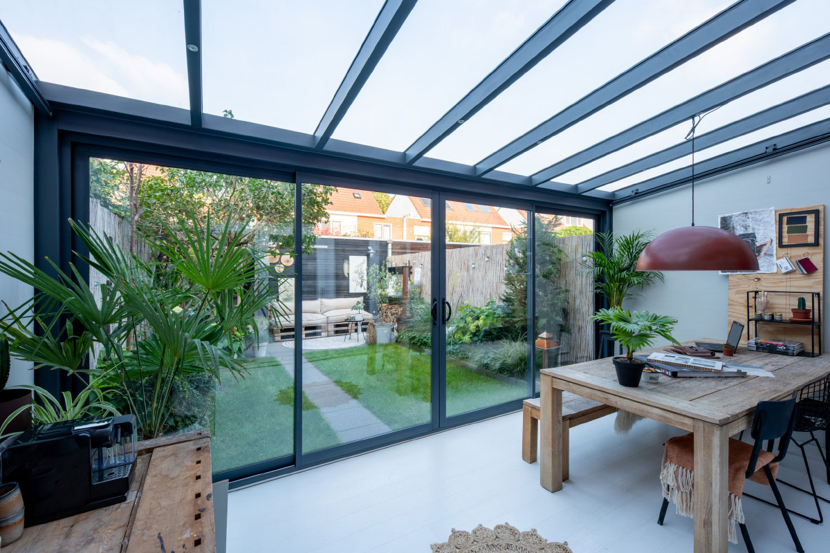 Moderne Schiebet&uuml;r aus Glas mit Blick auf einen Garten und Terrasse bei sonnigem Wetter.