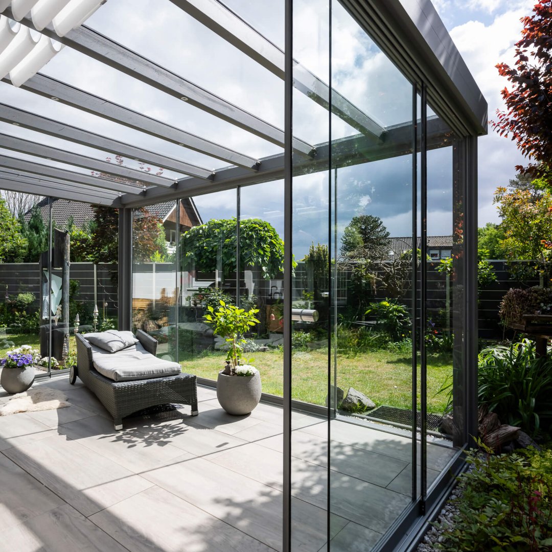Luxus-Wintergarten mit Aluminiumprofilen und Glasfronten – lichtdurchfluteter Wohnraum mit Blick in den Garten.