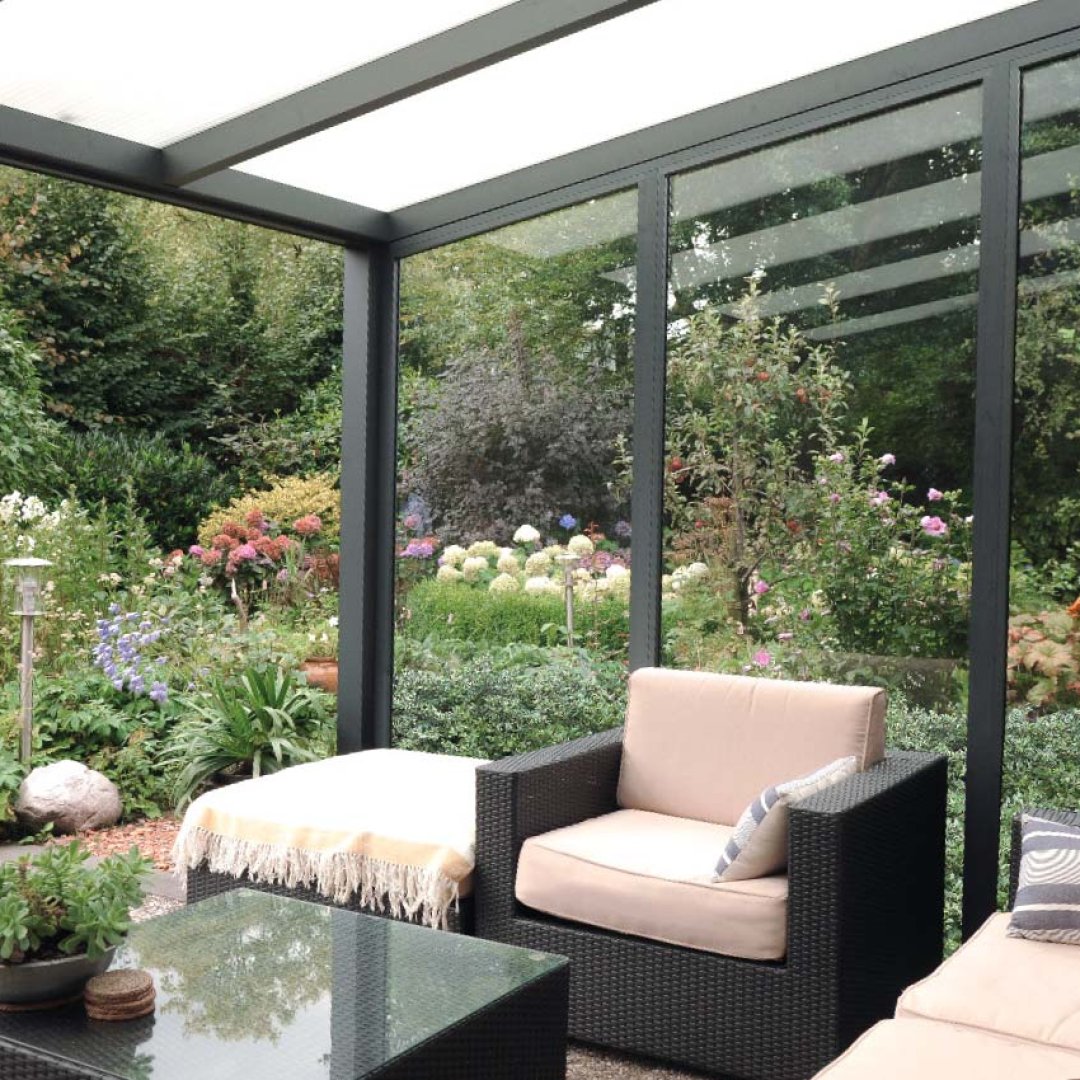 Luxus-Wintergarten mit Aluminiumprofilen und Glasfronten – lichtdurchfluteter Wohnraum mit Blick in den Garten.