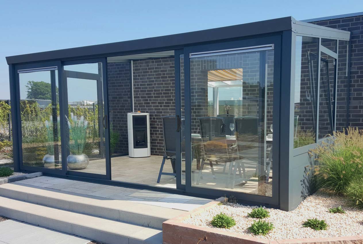 Wintergarten mit Schiebetür aus Aluminium und Glas, ideal für sonnige Tage im Garten.